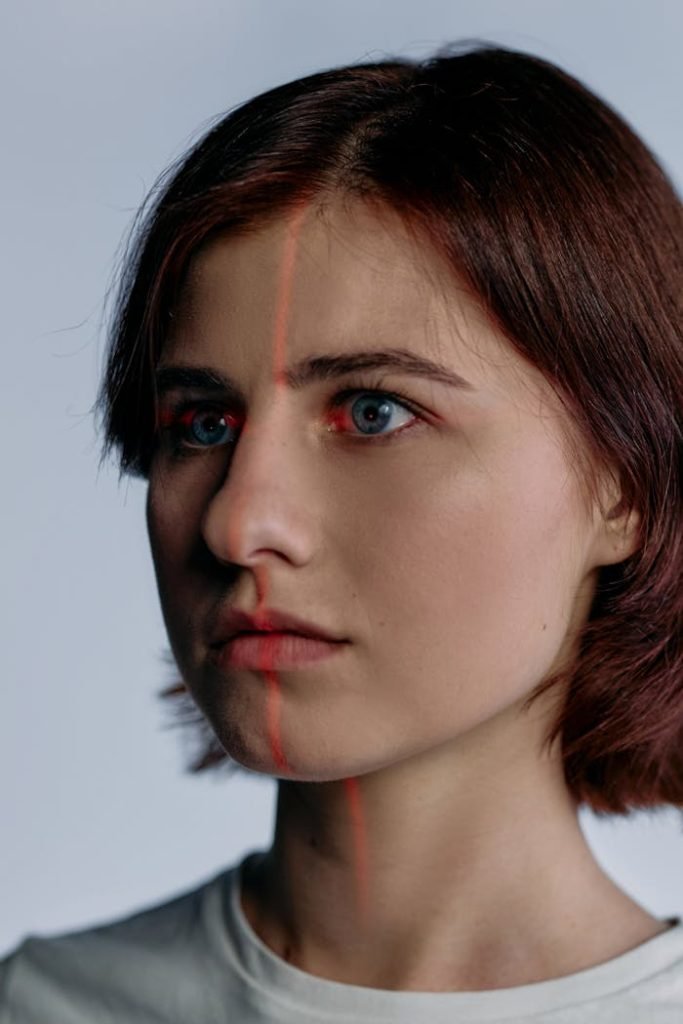 close-up-photo-of-woman-8090150 Profile of a caucasian woman with red laser lines on her face, suggesting advanced technology use.