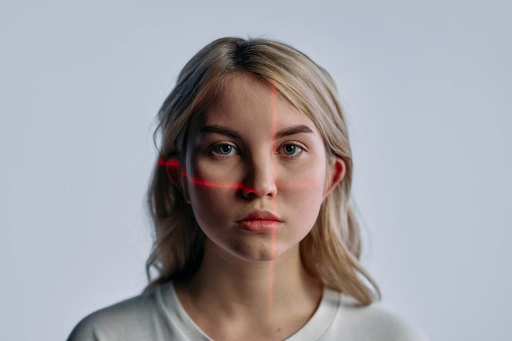 portrait-photo-of-woman-in-white-crew-neck-shirt-8090149 Close-up of a young woman with facial recognition lasers projected, symbolizing future technology.